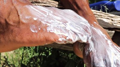 Kinky black guy rubs oil on his feet and teases outdoors