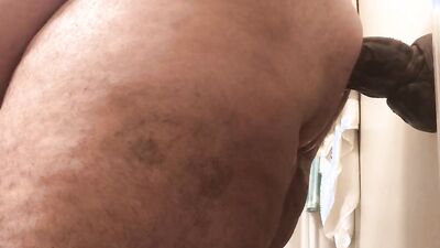 Fat guy sticks a big dildo to a wall and rides it
