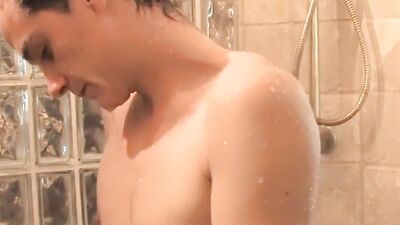 Slender twink strokes his hard cock while taking a shower