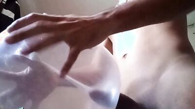 Naughty guy uses blown-up condom to play with his cock