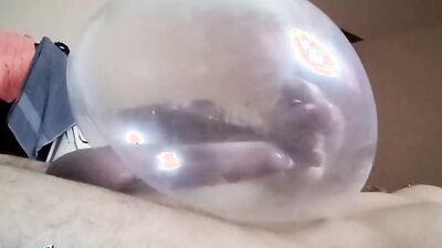 Naughty guy uses blown-up condom to play with his cock