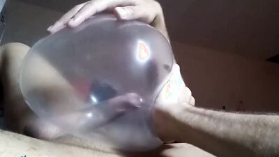 Naughty guy uses blown-up condom to play with his cock