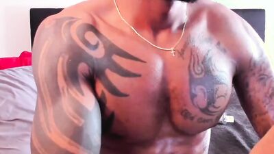 Inked black guy is chatting with his fans while jerking off