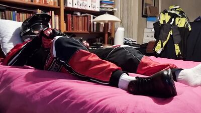 Horny biker is squeezing his dick while lying on that bed