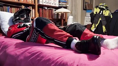 Horny biker is squeezing his dick while lying on that bed