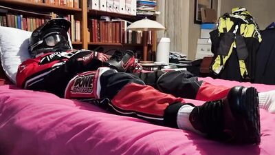 Horny biker is squeezing his dick while lying on that bed