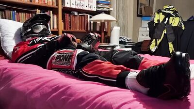 Horny biker is squeezing his dick while lying on that bed