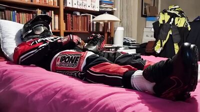 Horny biker is squeezing his dick while lying on that bed