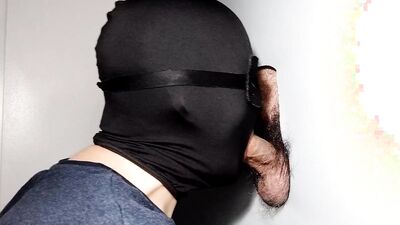 Cock is sucked through a gloryhole by a masked gimp