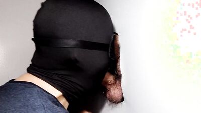 Cock is sucked through a gloryhole by a masked gimp