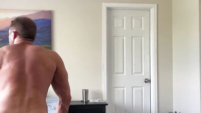 Muscle jock flexing and stroking cock while folding laundry
