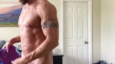 Muscle jock flexing and stroking cock while folding laundry