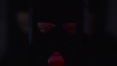 Masked gimp wraps his lips around a massive dildo and sucks it