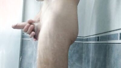 Amateur lad is playing with his huge dick while taking a shower