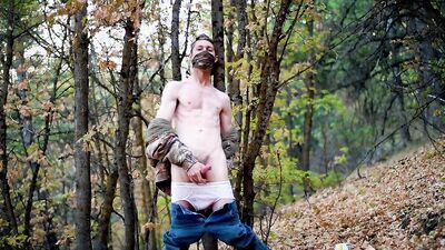 Skinny masked teen is playing with a pecker inside the forest