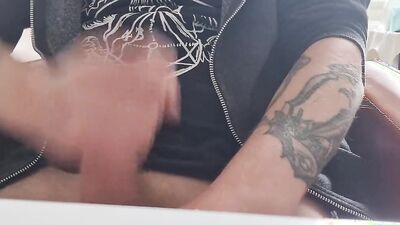 Tattooed fellow is jerking his dick in front of the phone