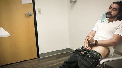 Bearded chap is stroking his hard prick inside the sperm bank