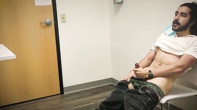 Bearded chap is stroking his hard prick inside the sperm bank