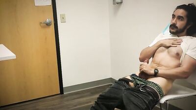 Bearded chap is stroking his hard prick inside the sperm bank