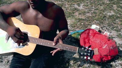 Amateur African chap is playing a guitar in front of the cam