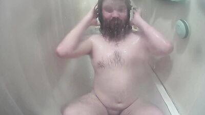 Longhaired chubby fellow is jerking his prick inside the hot shower