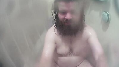 Longhaired chubby fellow is jerking his prick inside the hot shower