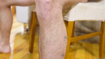 Handsome tattooed bloke is jerking his willy on the couch