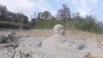 Perverted bloke is having fun out in the open inside the mud