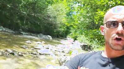 Perverted dude is playing with his dick next to a river