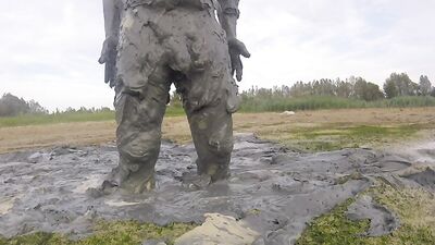 Amateur fellow is covering himself in mud out in the open
