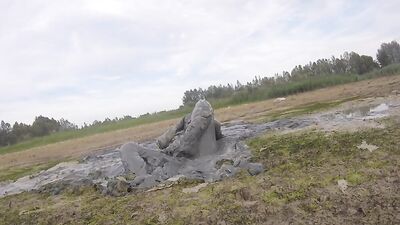 Amateur fellow is covering himself in mud out in the open