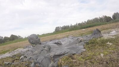 Amateur fellow is covering himself in mud out in the open