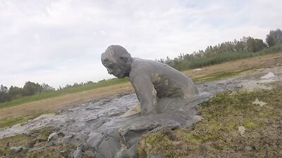 Amateur fellow is covering himself in mud out in the open