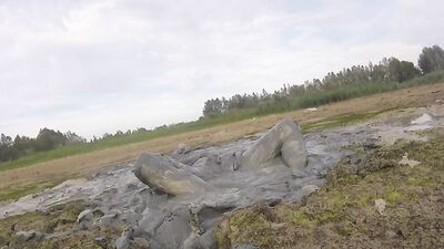 Amateur fellow is covering himself in mud out in the open