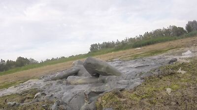Amateur fellow is covering himself in mud out in the open
