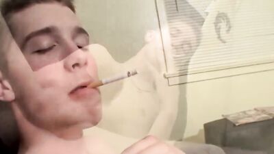 Straight lad is jerking his cock while he's smoking a cigarette