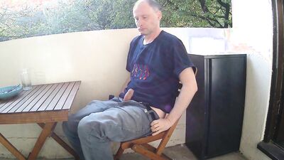 Man outside on the balcony eating lunch undress and starts wanking his penis is soon erect