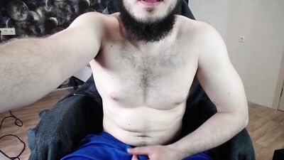 A muscular guy jerks off a big dick through his shorts