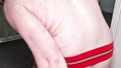 Toying around at top of stairs in red jockstrap and socks
