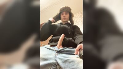 A guy in a jacket and a hat masturbates and cums upside down on his jacket