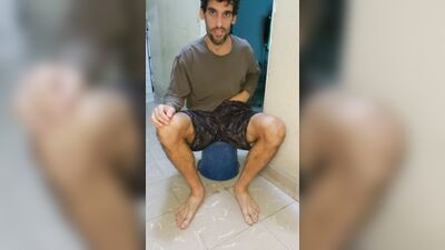 Unshaven guy jerks off barefoot on the floor