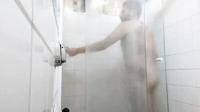 handsome guy brushing his teeth in the shower.