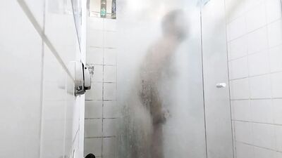 handsome guy brushing his teeth in the shower.
