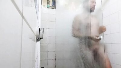 handsome guy brushing his teeth in the shower.